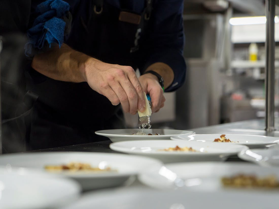 A chef carefully plating a dish in a professional kitchen, illustrating the craft Catertoo is built to support.