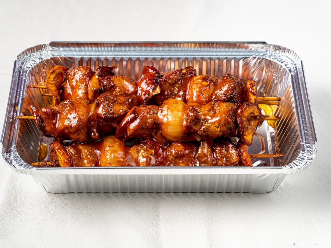Foil-tray barbecue and catered drop-off food packaged and ready for delivery to a corporate client.
