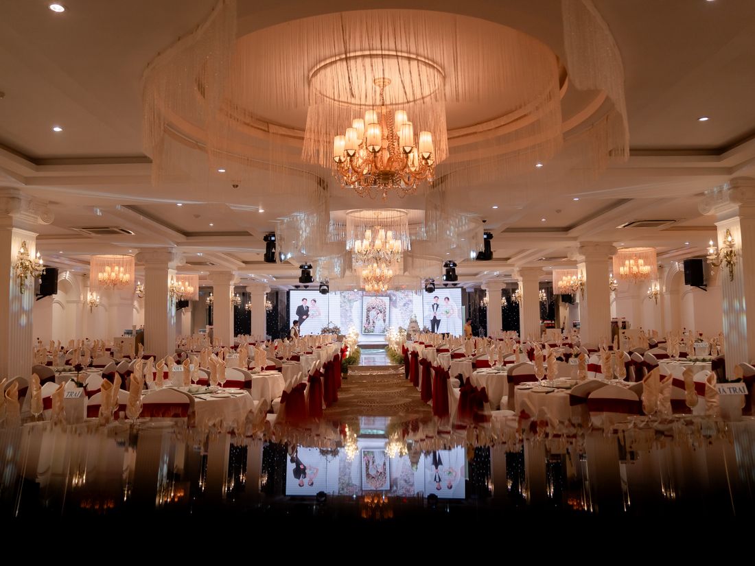 A grand hotel ballroom set for a catered banquet event with round tables and formal place settings.