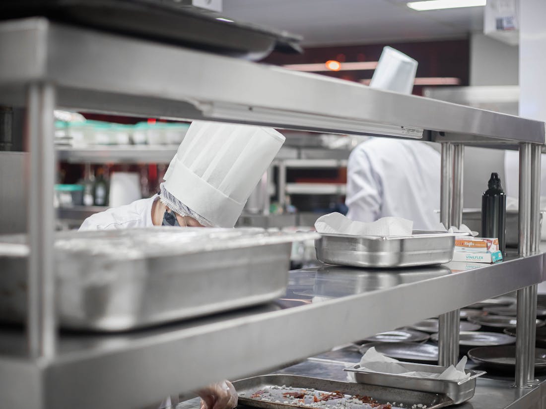 Restaurant kitchen staff preparing a catered order - trays of food ready for an off-premise event.